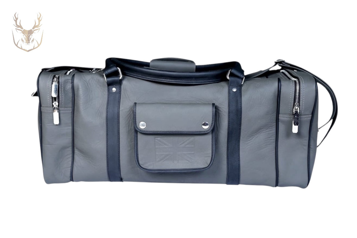 LuxeAura’s Gray Handcrafted Italian Leather Duffle Bag features premium cowhide, black straps, a front pocket with an embossed flag, and silver zippers. Displayed on white with a deer head logo in the top left corner.