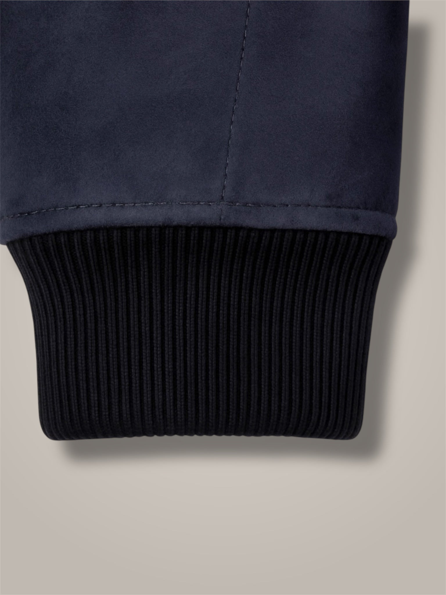 Close-up of navy blue fabric with black ribbed trim on a beige background