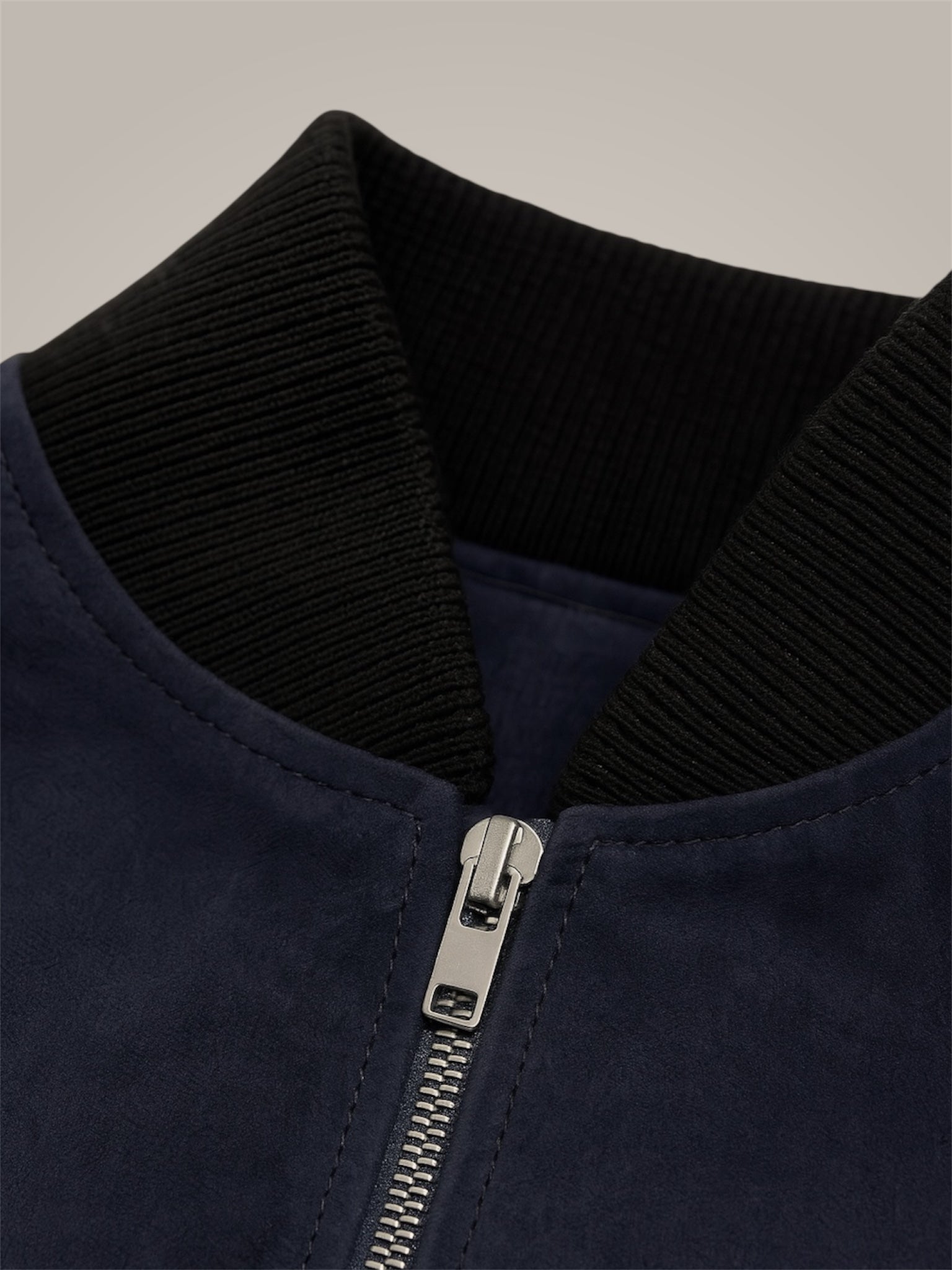 Close-up of a navy blue jacket with a zipper on a neutral background