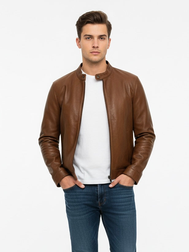 Man wearing a brown leather jacket over a white shirt and blue jeans on a light gray background