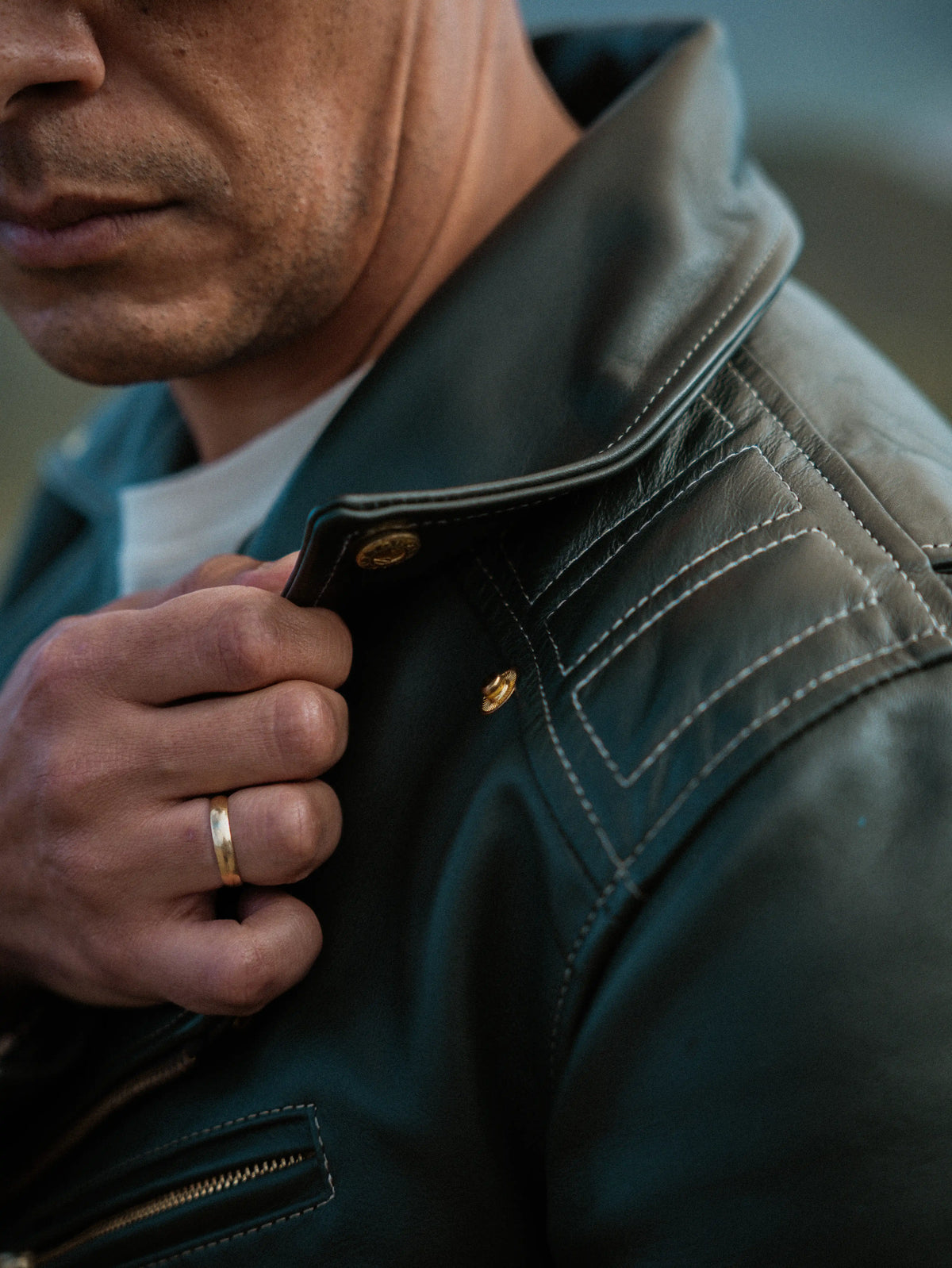 Close-up of a person wearing a dark jacket with a gold ring on their finger.