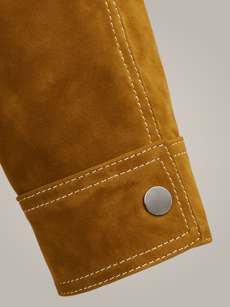 Close-up of a mustard suede leather jacket with a button on a gray background