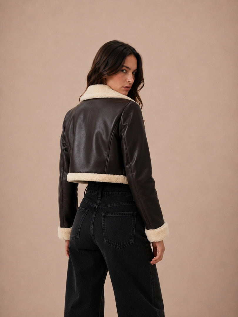 Woman wearing a black leather jacket with white fur trim on a beige background