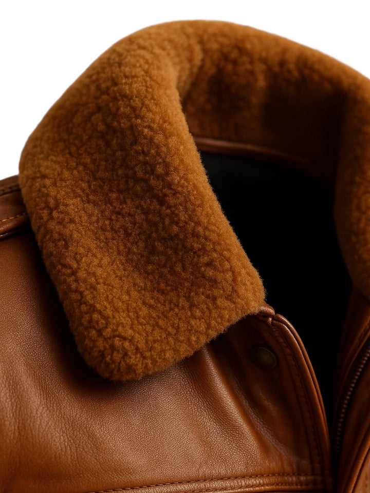 Close-up of a brown leather jacket with fur lining on a white background