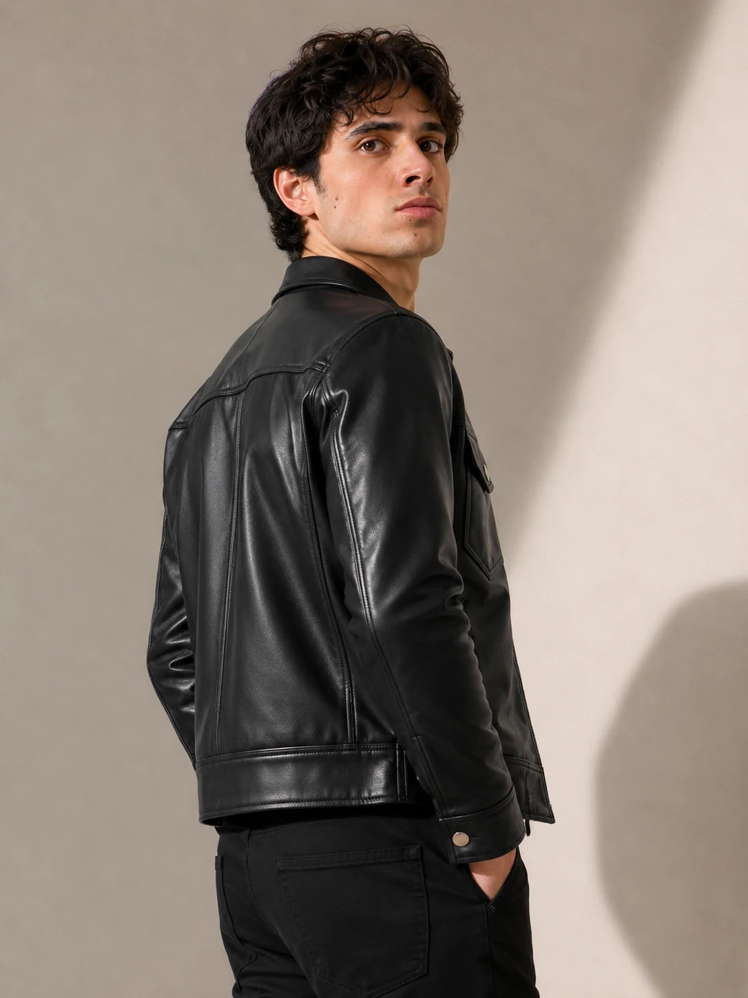 Man wearing a black leather jacket against a neutral background
