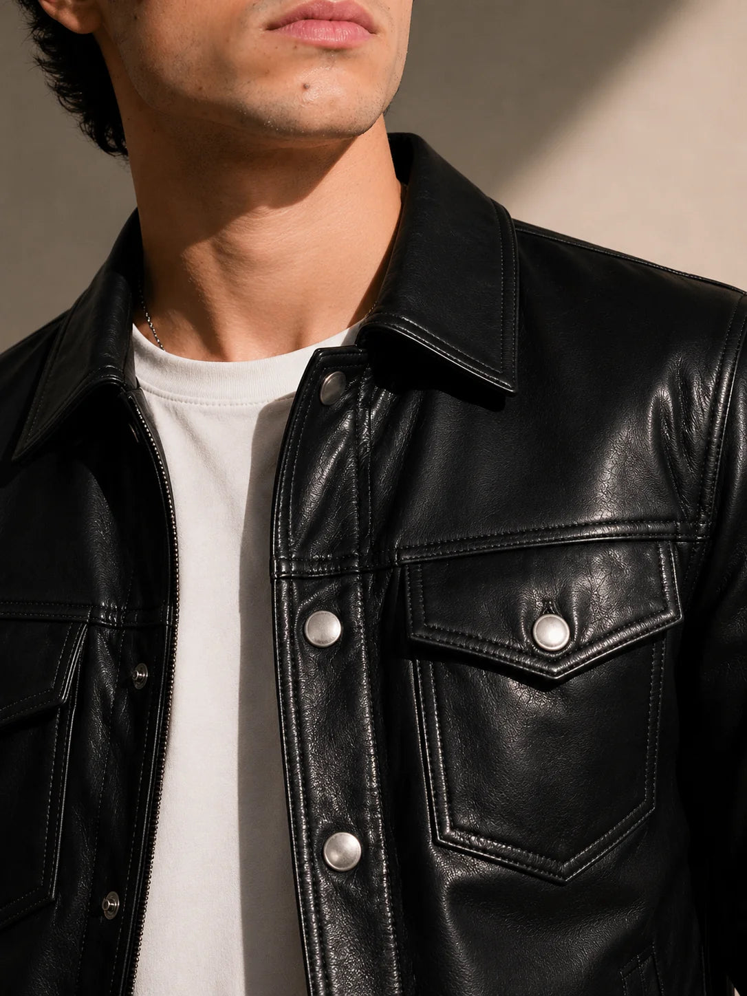 Close-up of a person wearing a black leather jacket with a neutral background