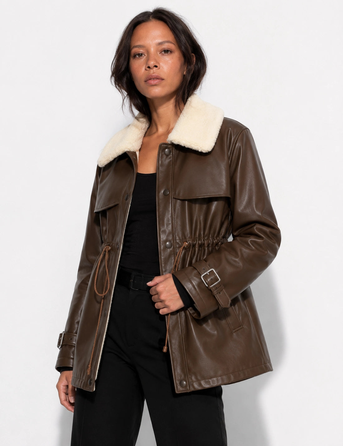 Woman wearing a brown leather jacket with white fur lining on a white background