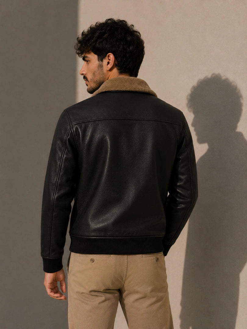 Man wearing a black leather jacket with a beige collar against a plain background