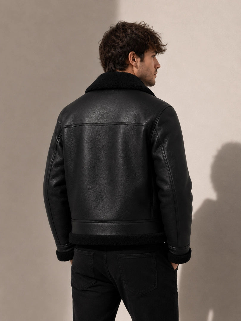 Man wearing a black leather jacket against a beige wall