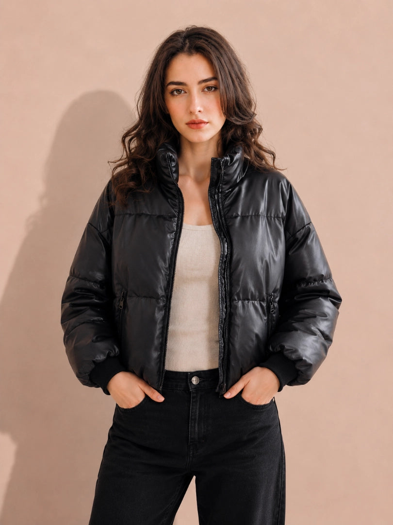 Woman wearing a black puffer jacket against a beige background