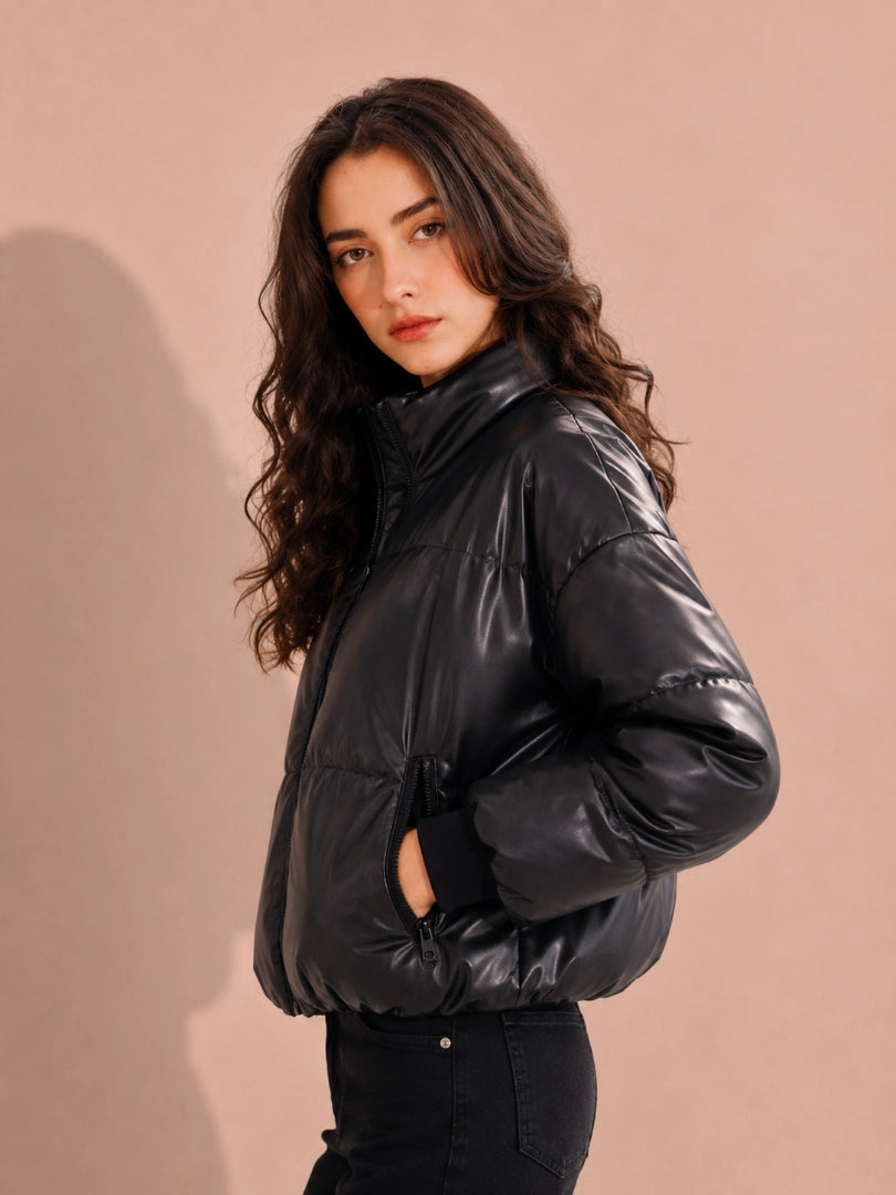 Woman wearing a black puffer jacket against a beige background