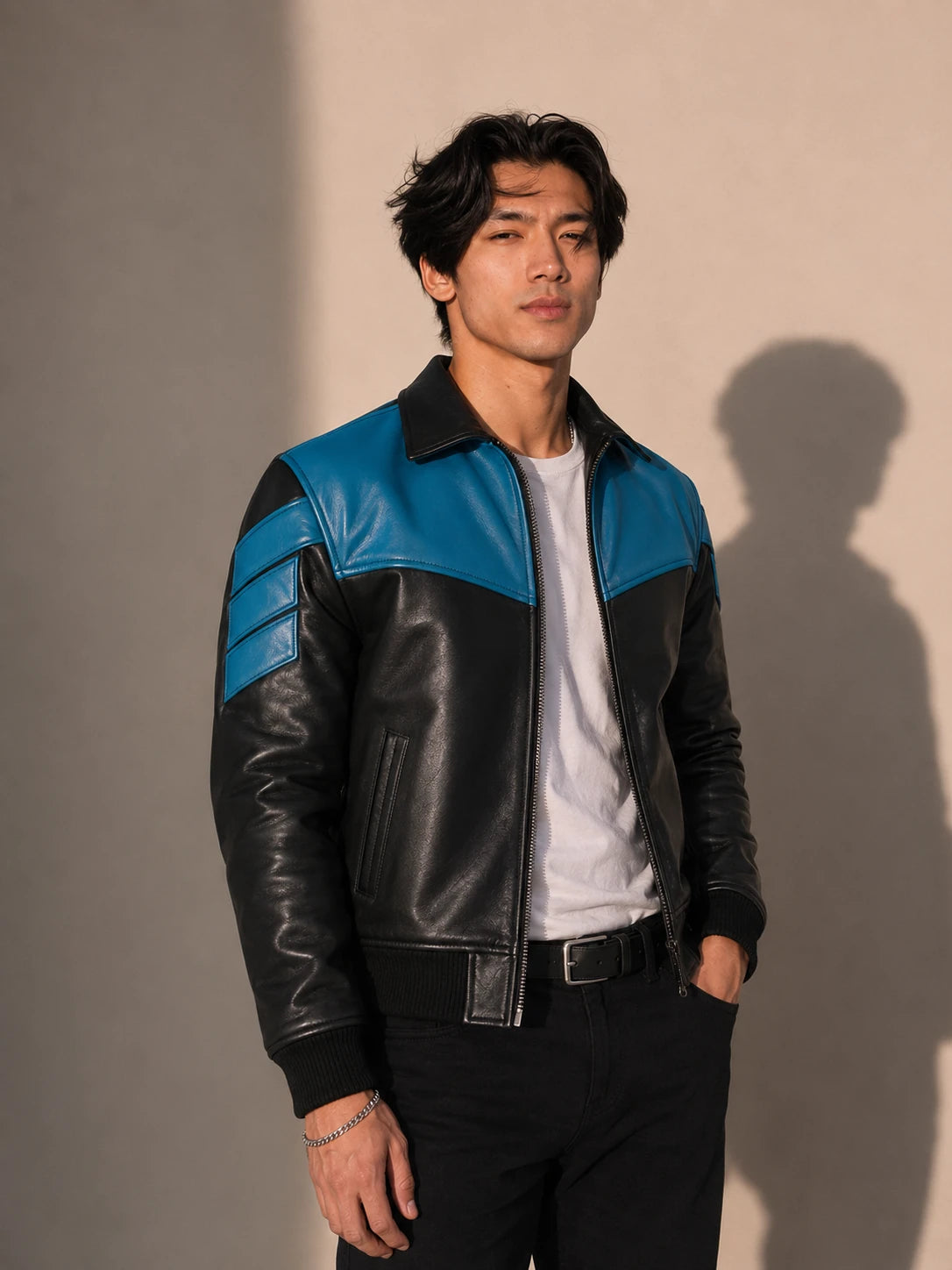 Man wearing a black and blue leather jacket against a plain background