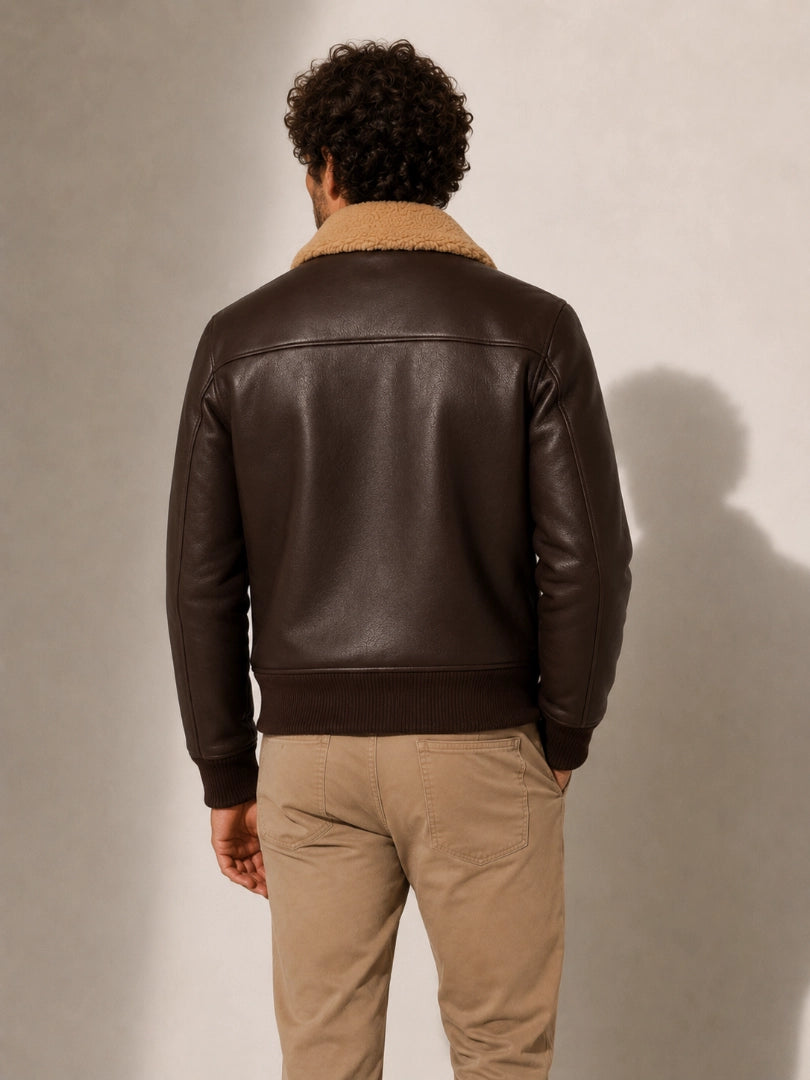 Man wearing a brown leather jacket with a beige interior on a plain background