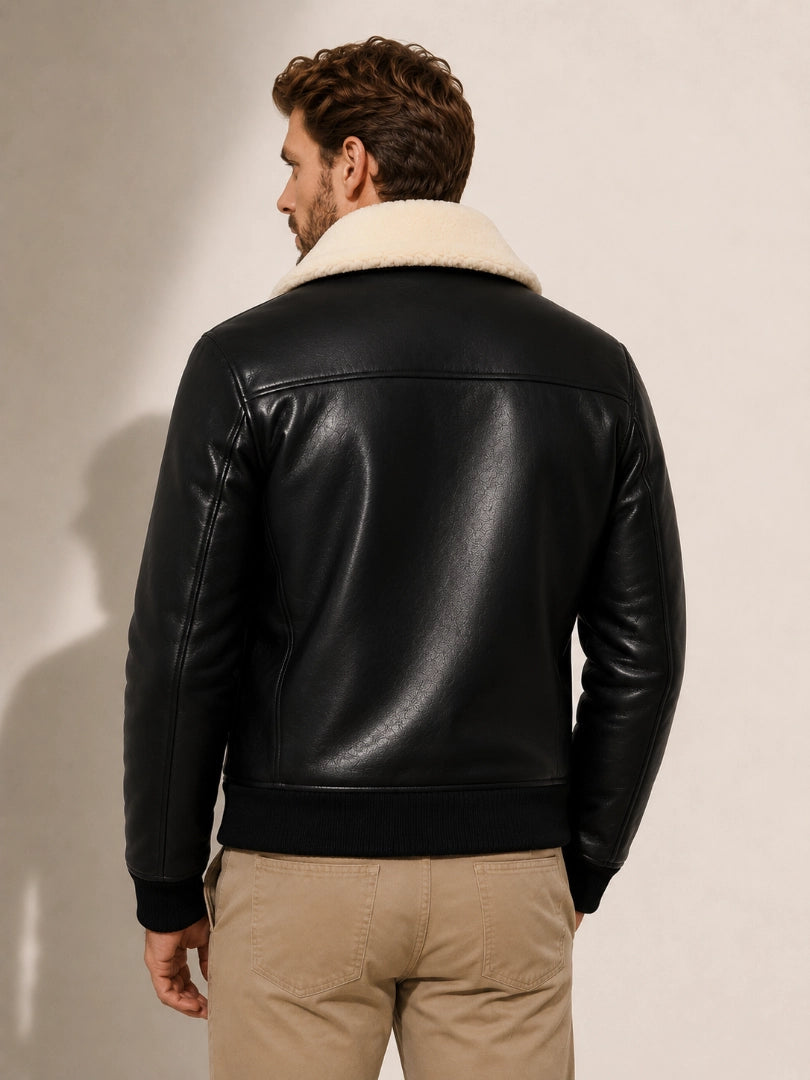 Man wearing a black leather jacket with beige fur lining on a plain background