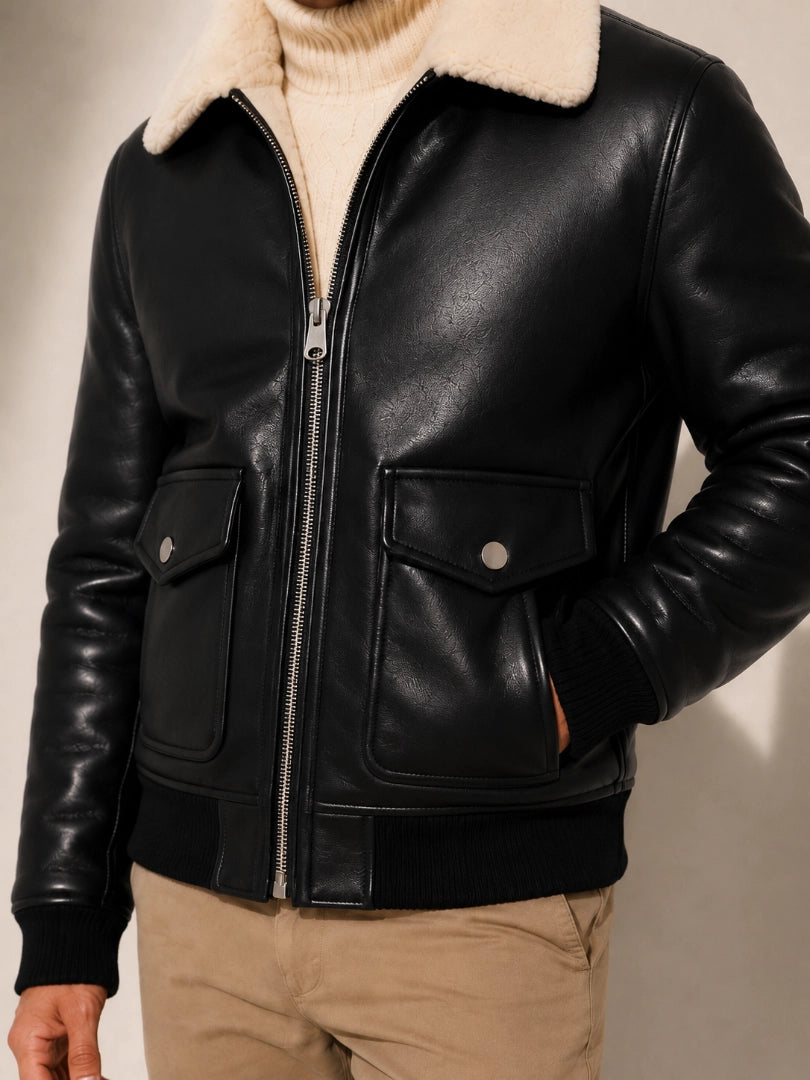 Black leather jacket with beige interior lining on a neutral background