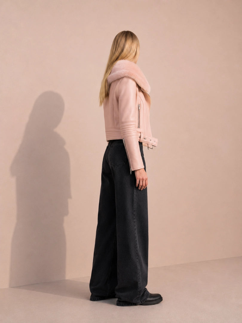 Woman wearing a pink jacket and black pants against a beige background