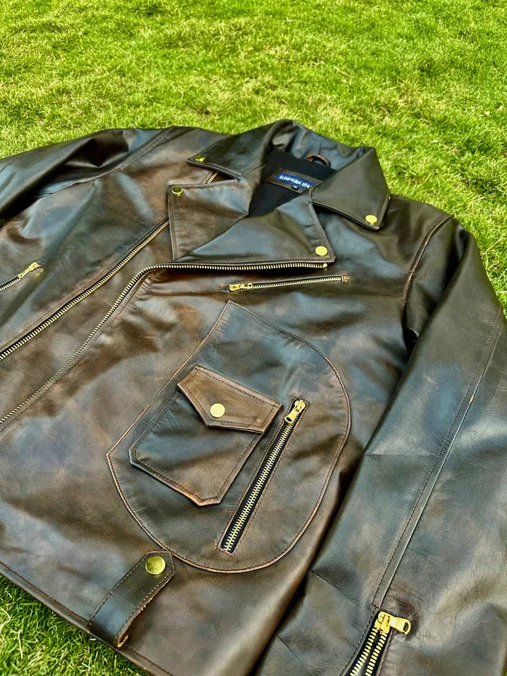 Brown leather jacket with gold zippers on a grassy background
