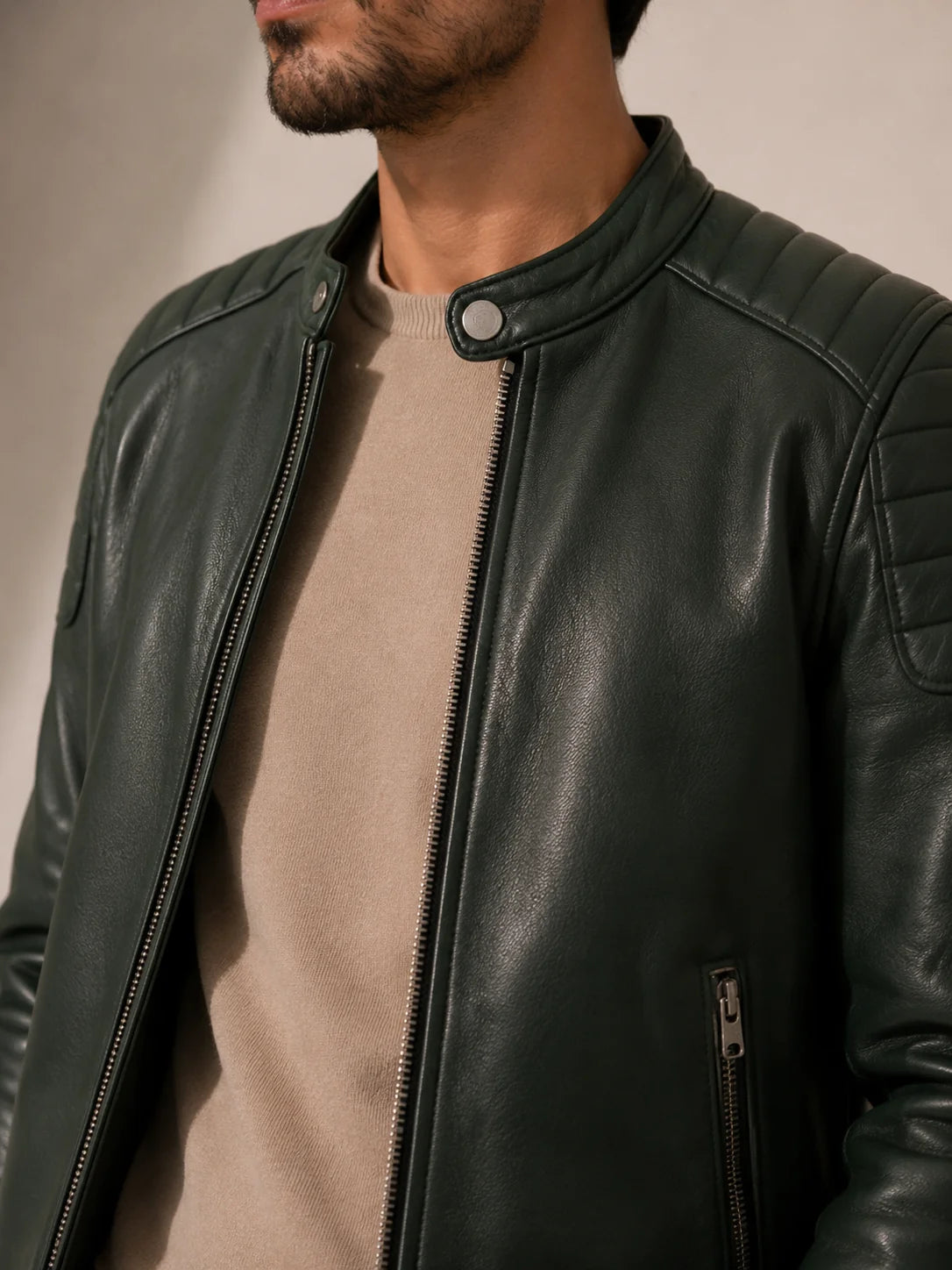 Man wearing a dark green leather jacket against a neutral background