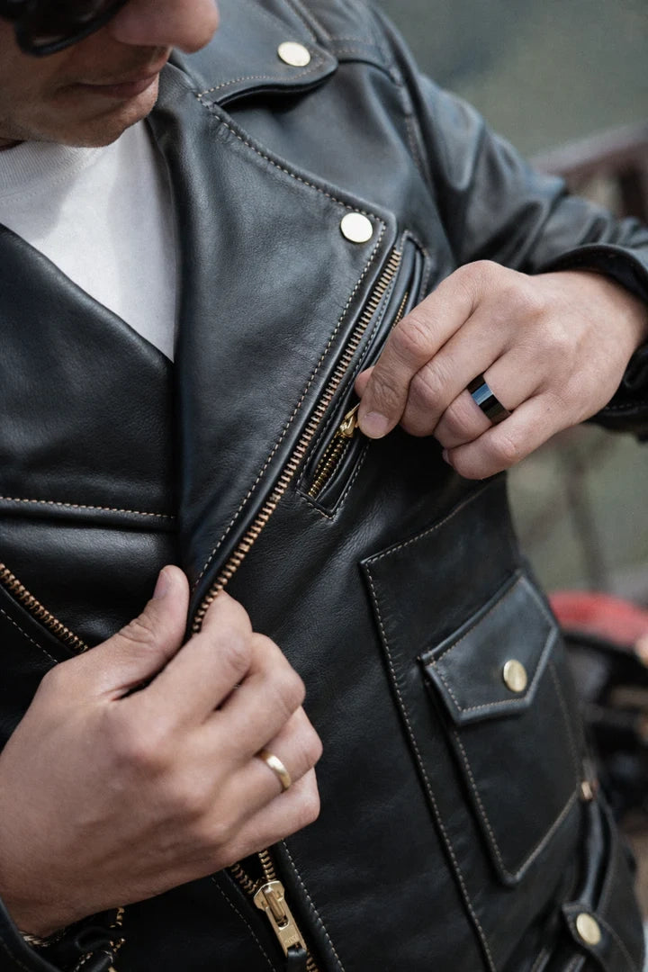 Person wearing a black leather jacket with gold zippers and buttons.