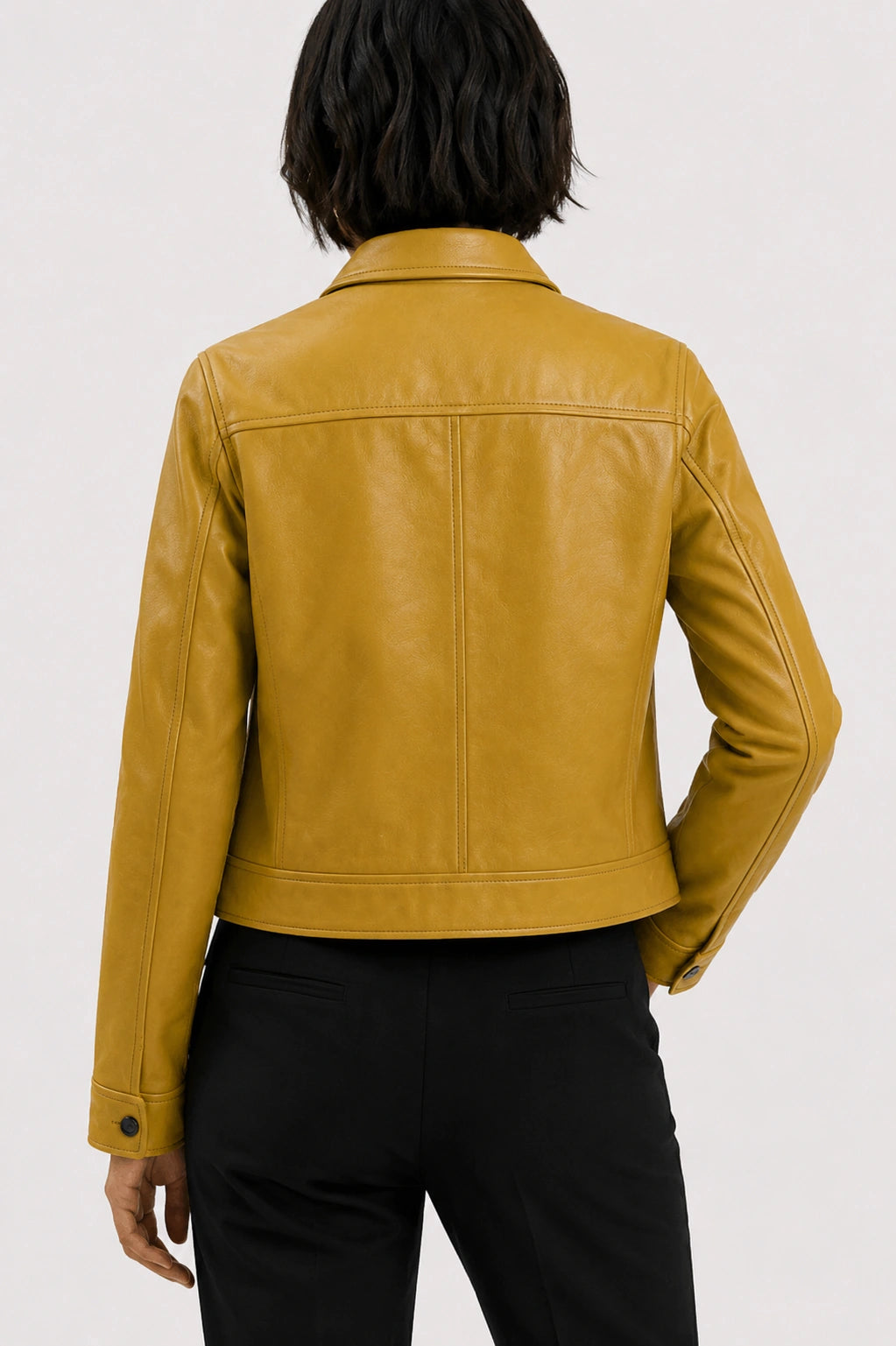 Person wearing a mustard yellow leather jacket on a white background