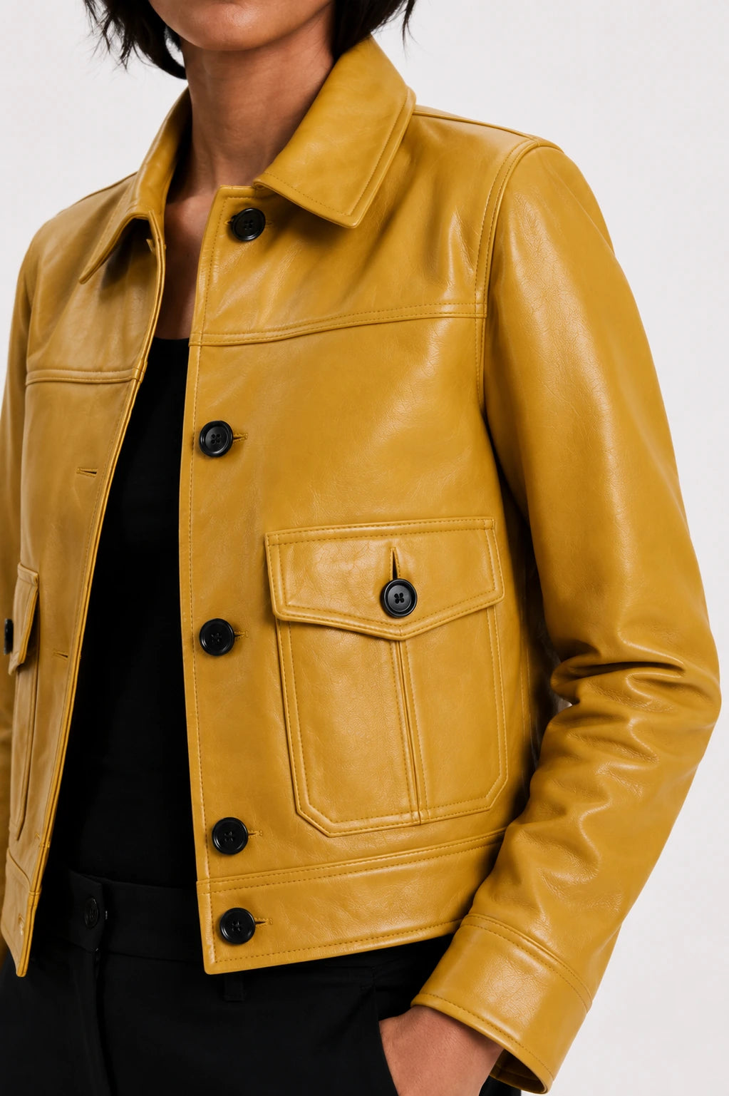 Yellow leather jacket with black buttons on a white background