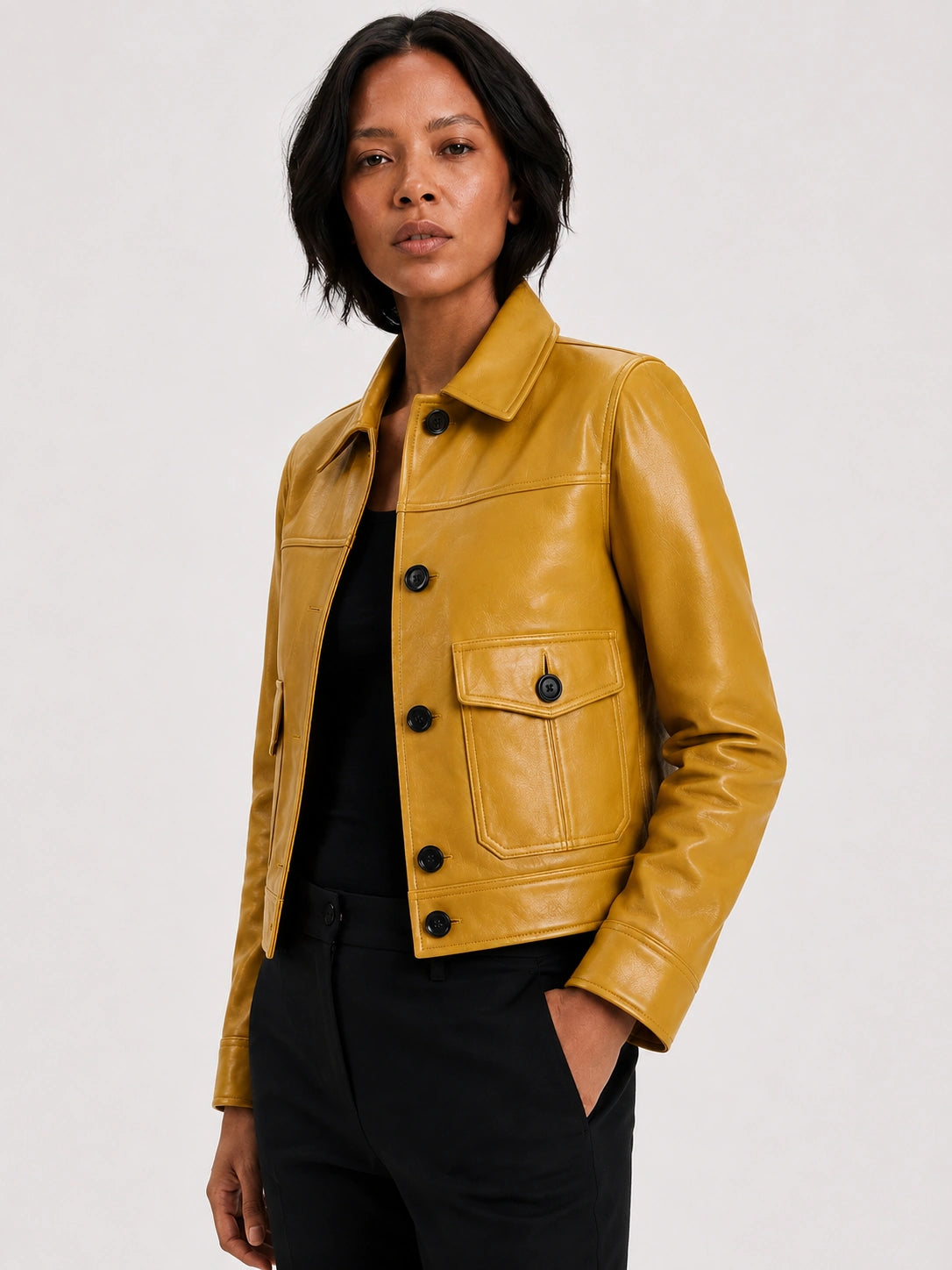 Woman wearing a mustard yellow leather jacket on a white background