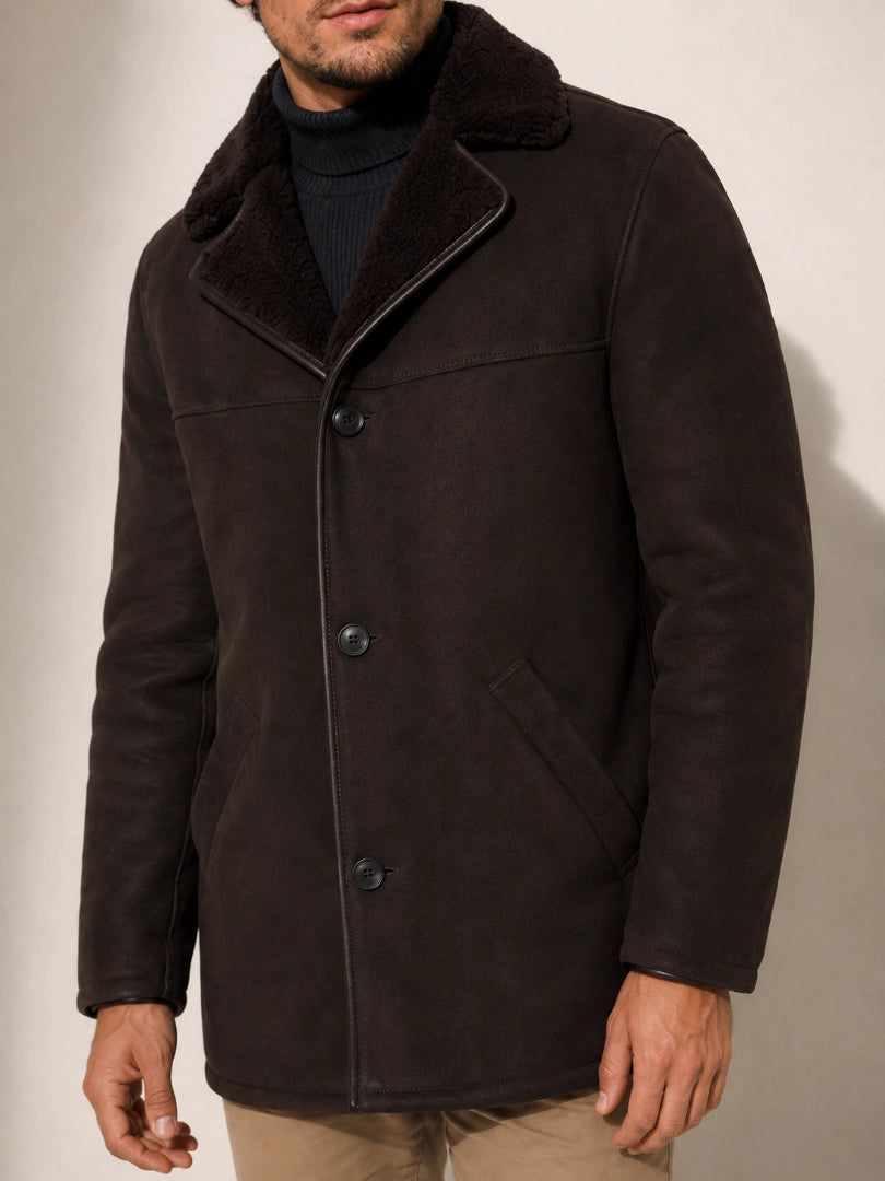 Man wearing a dark brown coat with a plain background