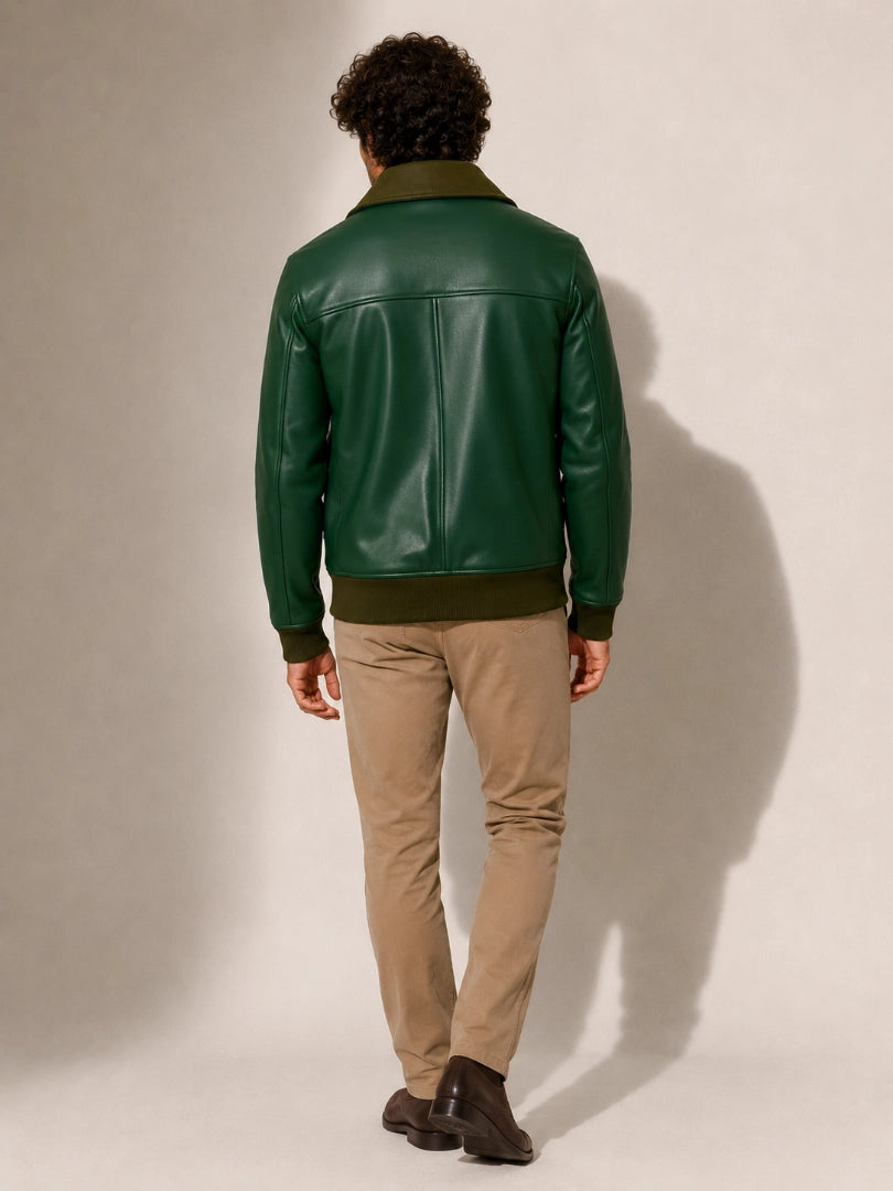 Person wearing a green leather jacket and beige pants against a plain background