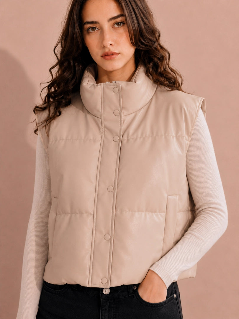 Woman wearing a beige puffer vest against a beige background