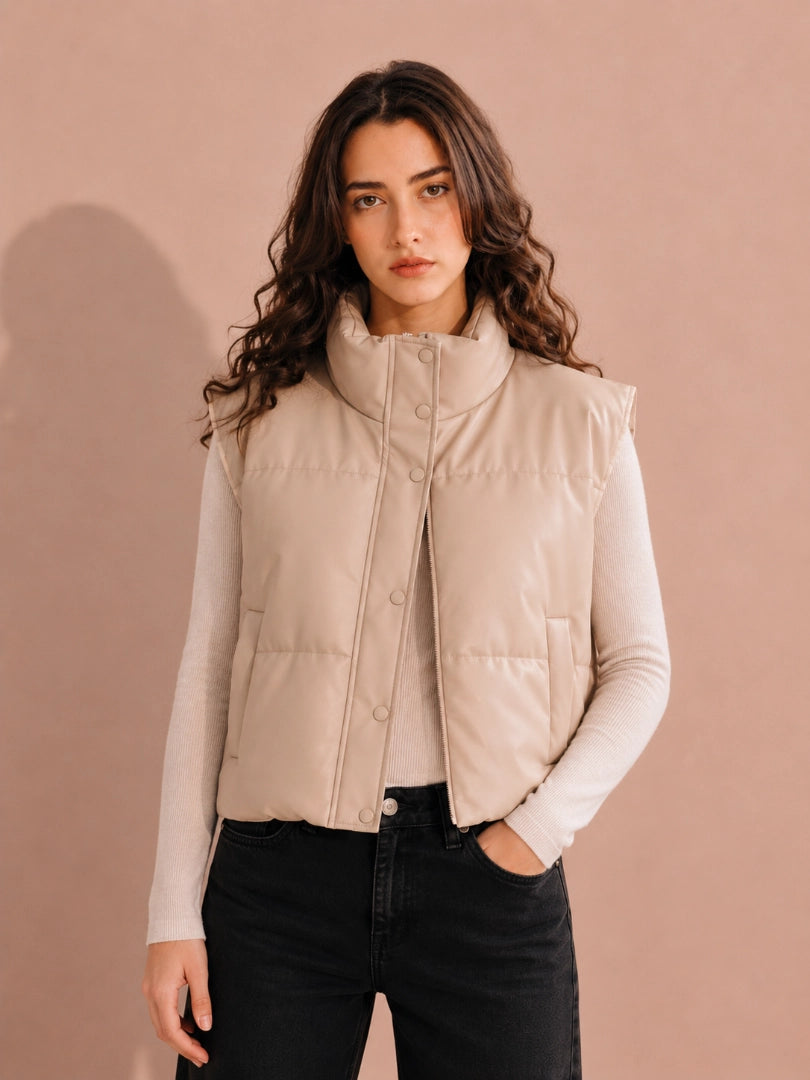 Woman wearing a beige puffer vest against a beige background