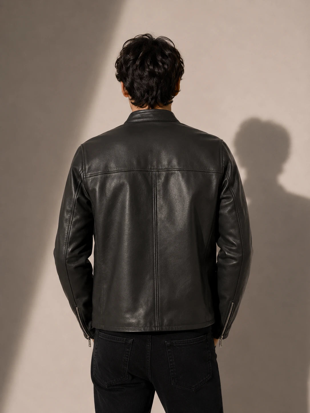Person wearing a black leather jacket against a plain background