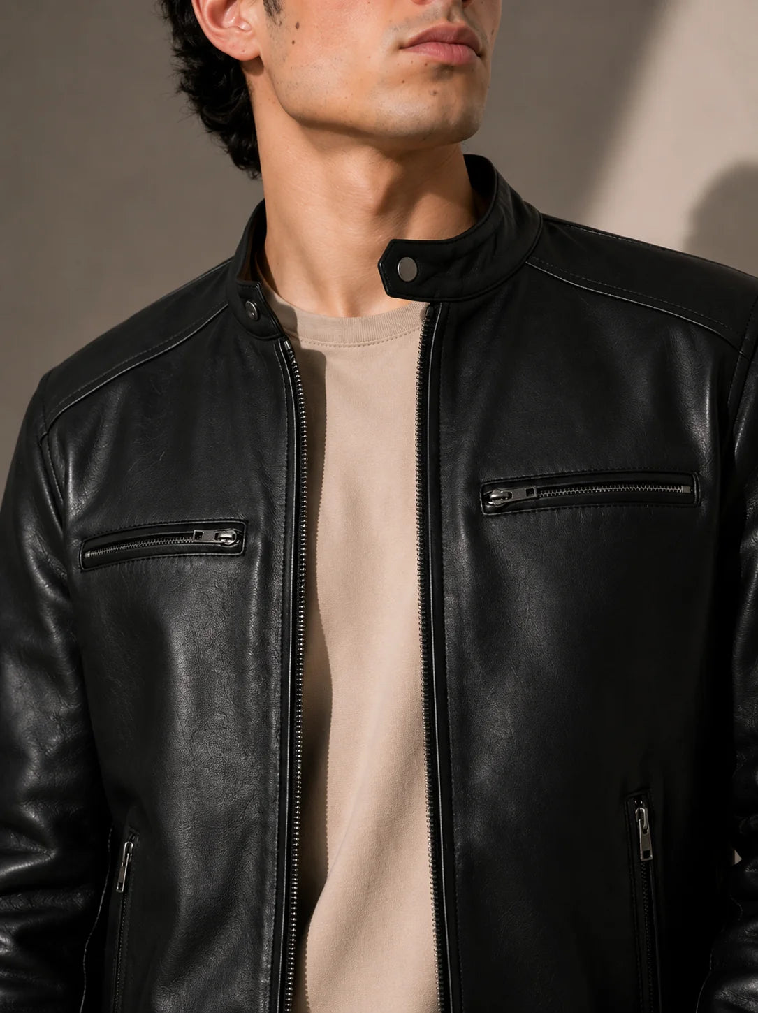 Man wearing a black leather jacket against a neutral background