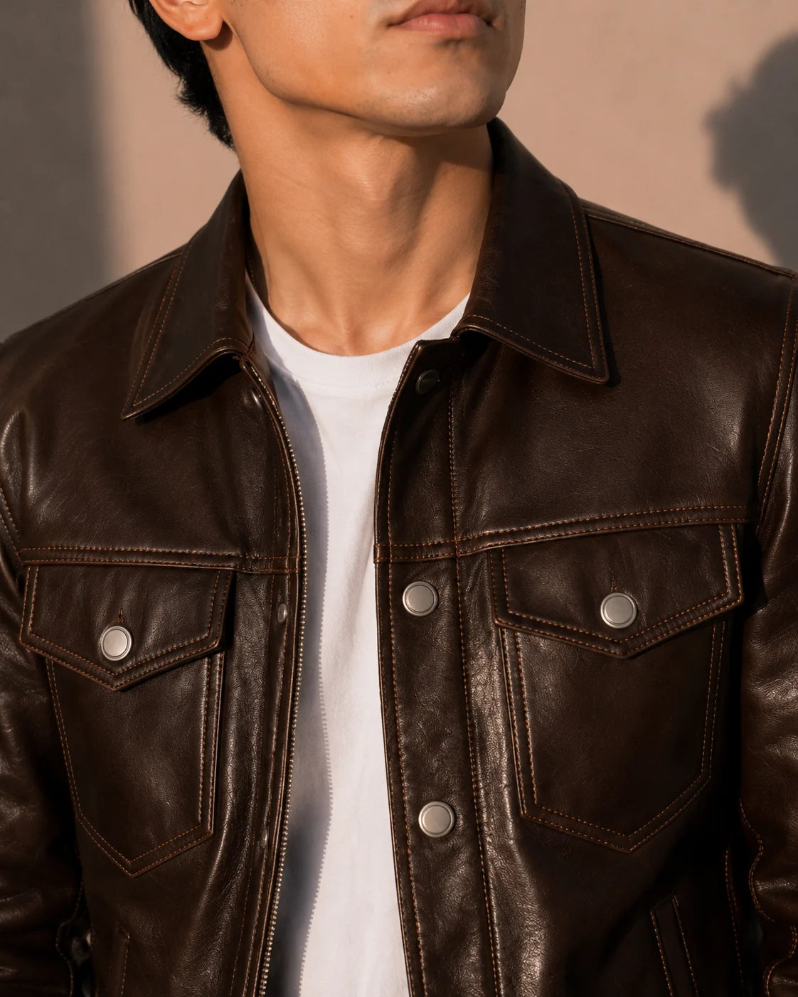Close-up of a person wearing a brown leather jacket with a neutral background