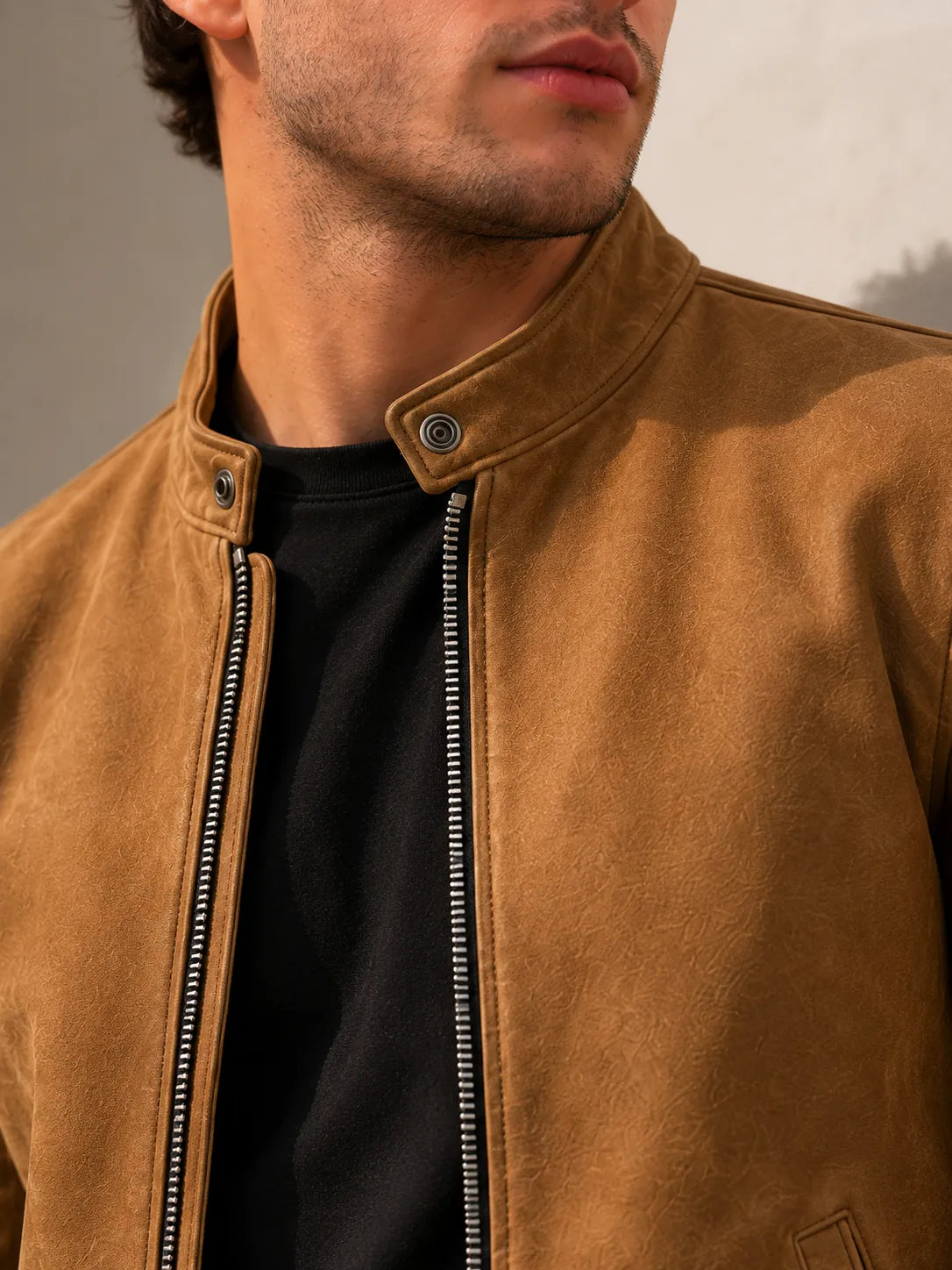 Close-up of a person wearing a brown leather jacket with a neutral background