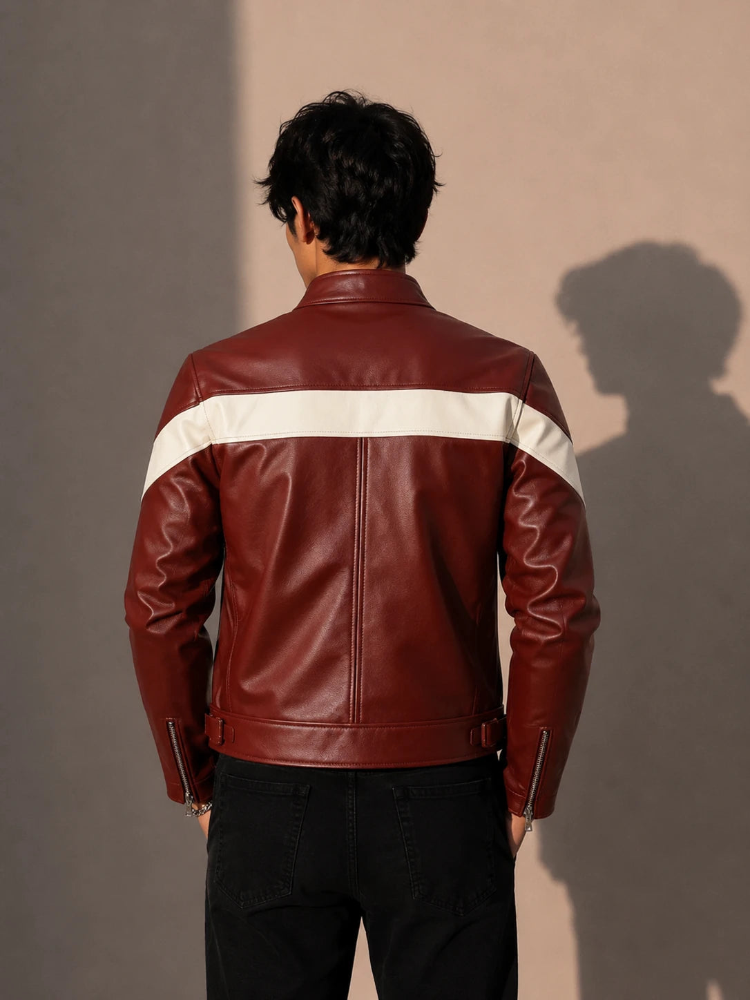 Person wearing a maroon leather jacket with a white stripe on a plain background