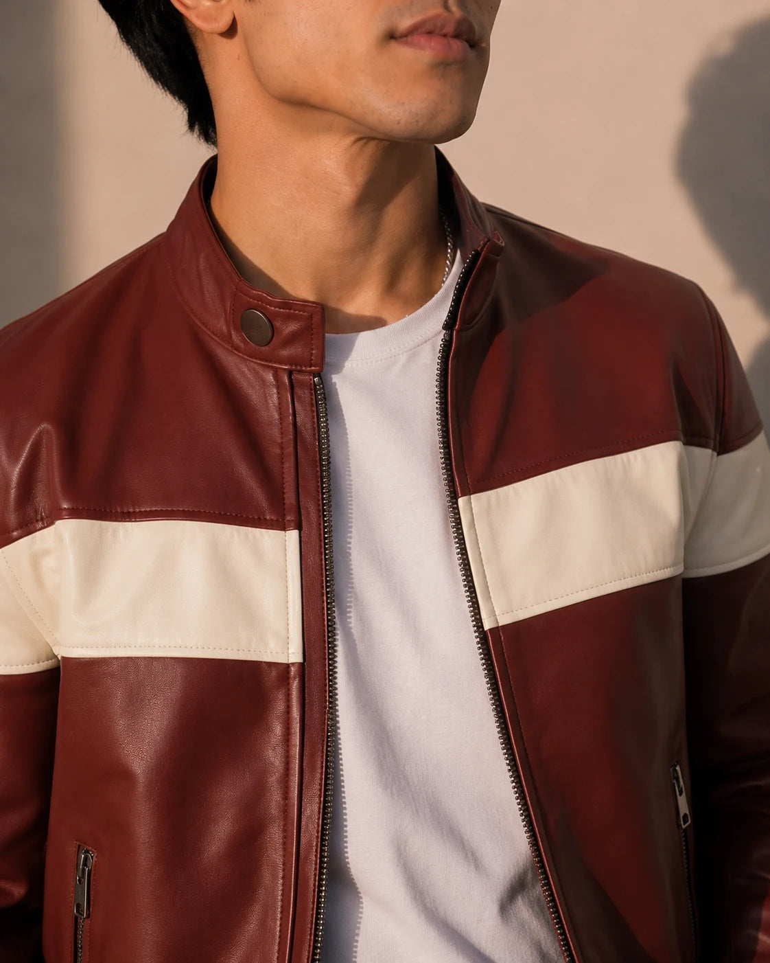 Man wearing a red and white leather jacket with a neutral background