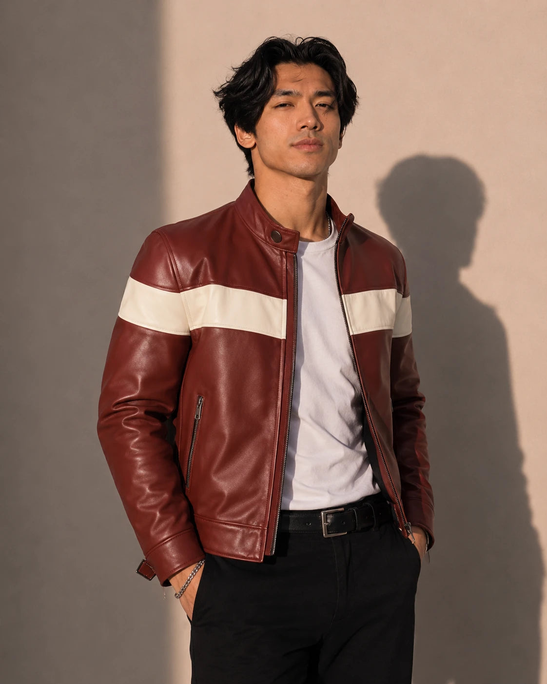 Man wearing a brown leather jacket with white stripes against a plain background