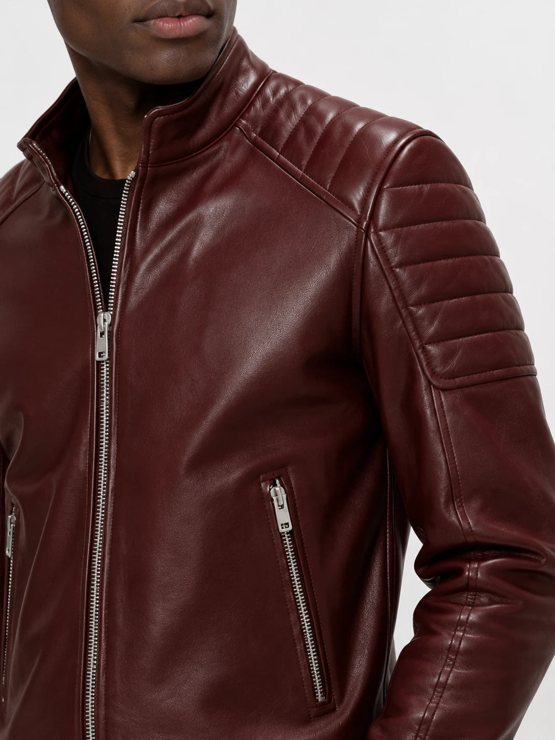 Close-up of a maroon leather jacket with zippers on a neutral background