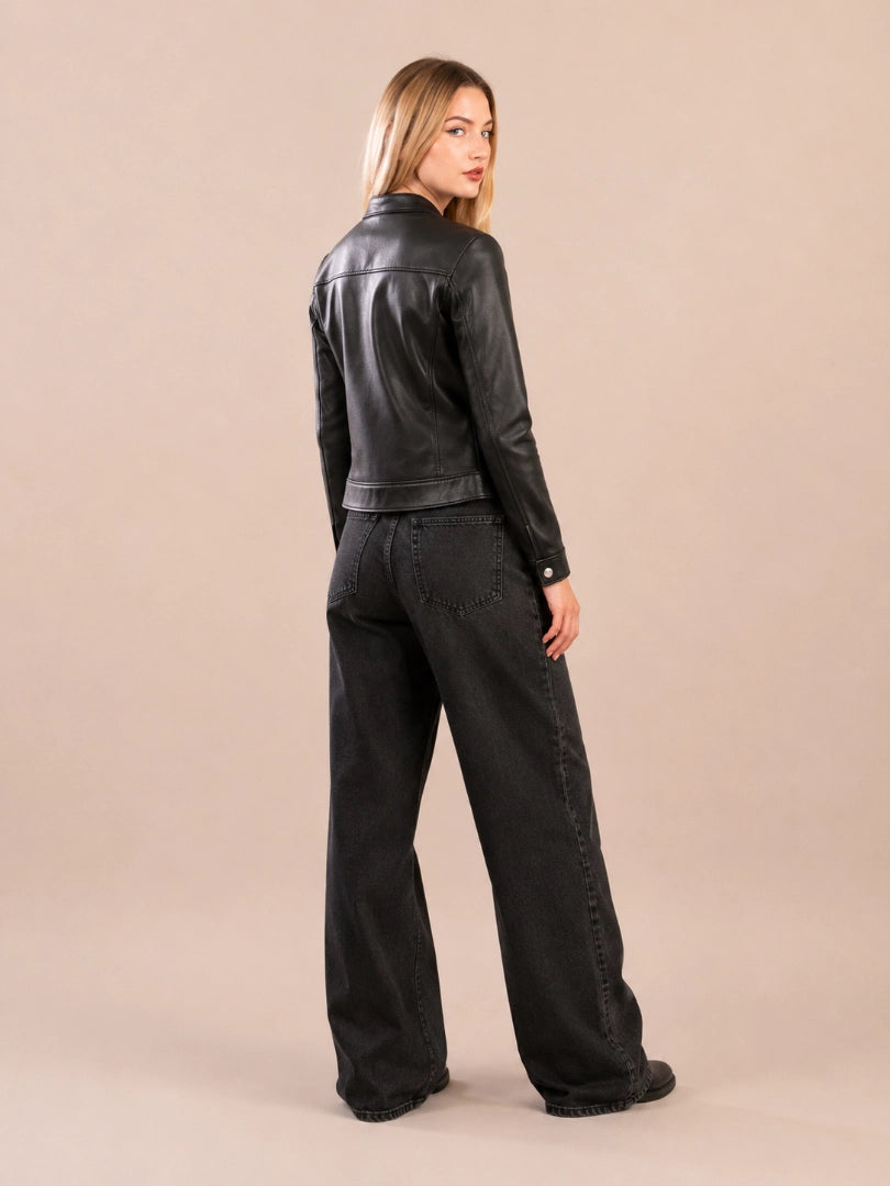 Woman wearing a black leather jacket and black pants on a beige background